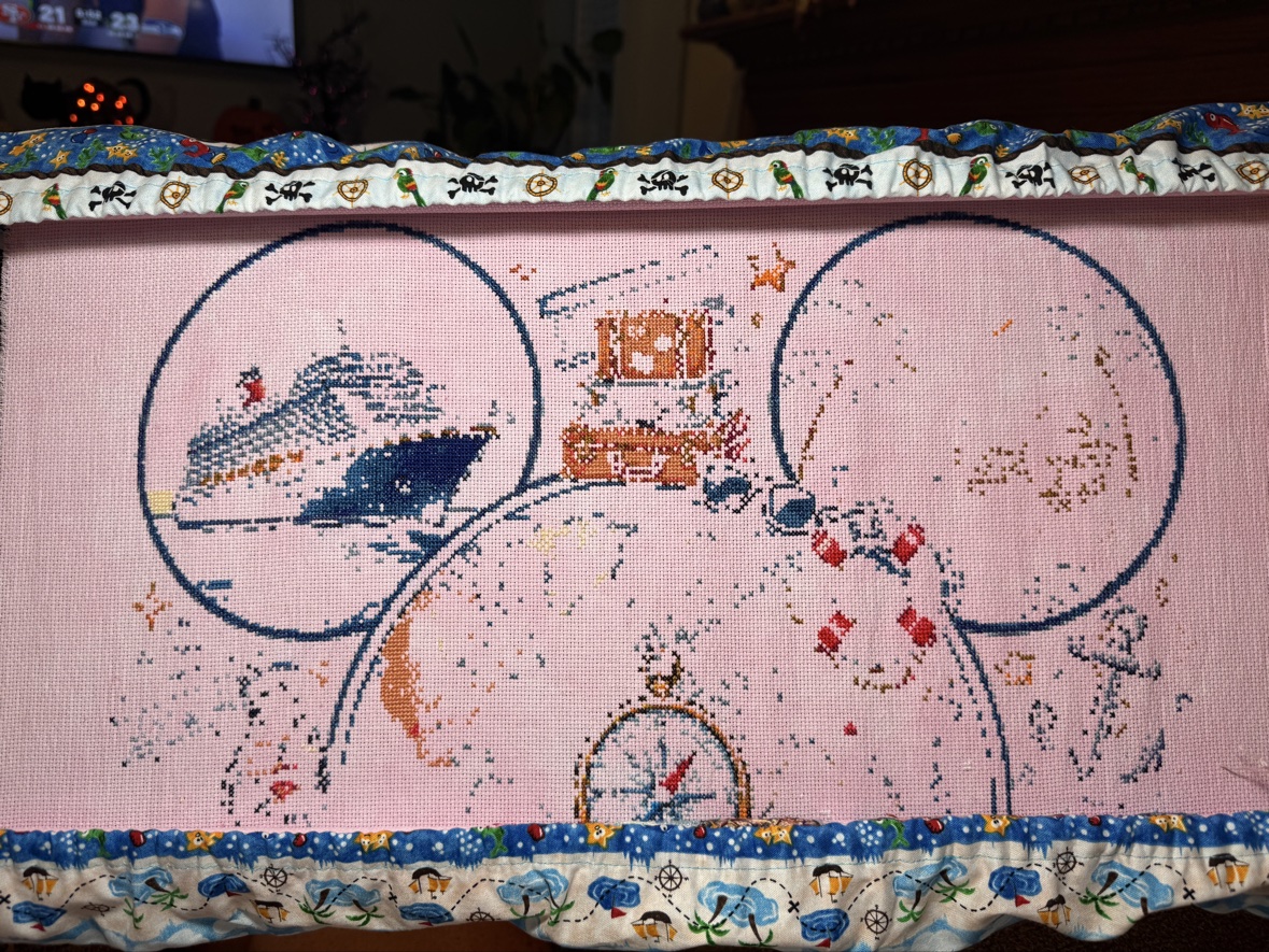 Anne Conrad&rsquo;s &ldquo;Magical Cruise&rdquo; cross stitch in progress on pale pink fabric in a scroll frame