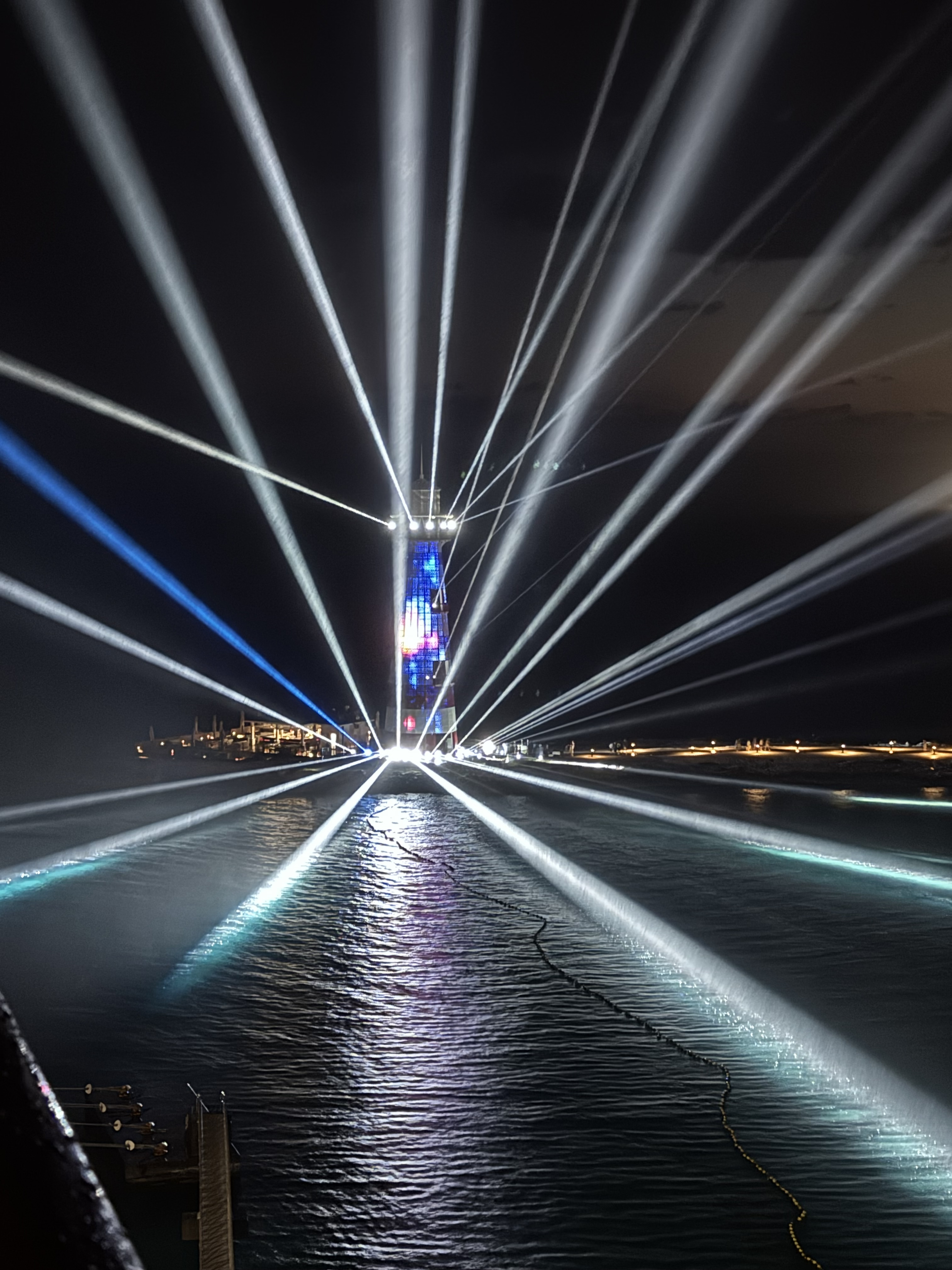 Beams of light radiating from the Ocean Cay lighthouse during its nighttime laser show
